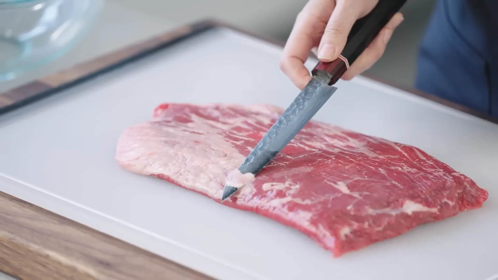 Trimming silver skin from flank steak with knife