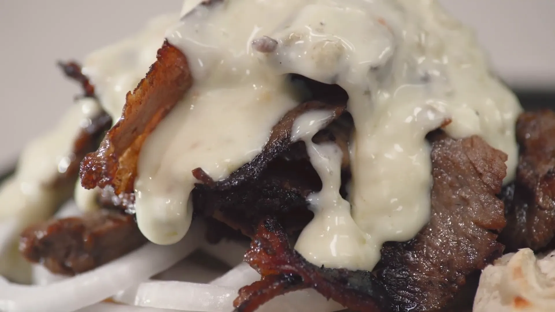 Pouring green chile queso over the reheated beef