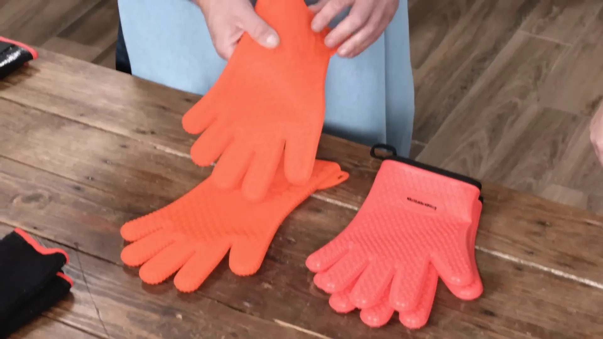 Brightly colored silicone grill gloves being wiped clean