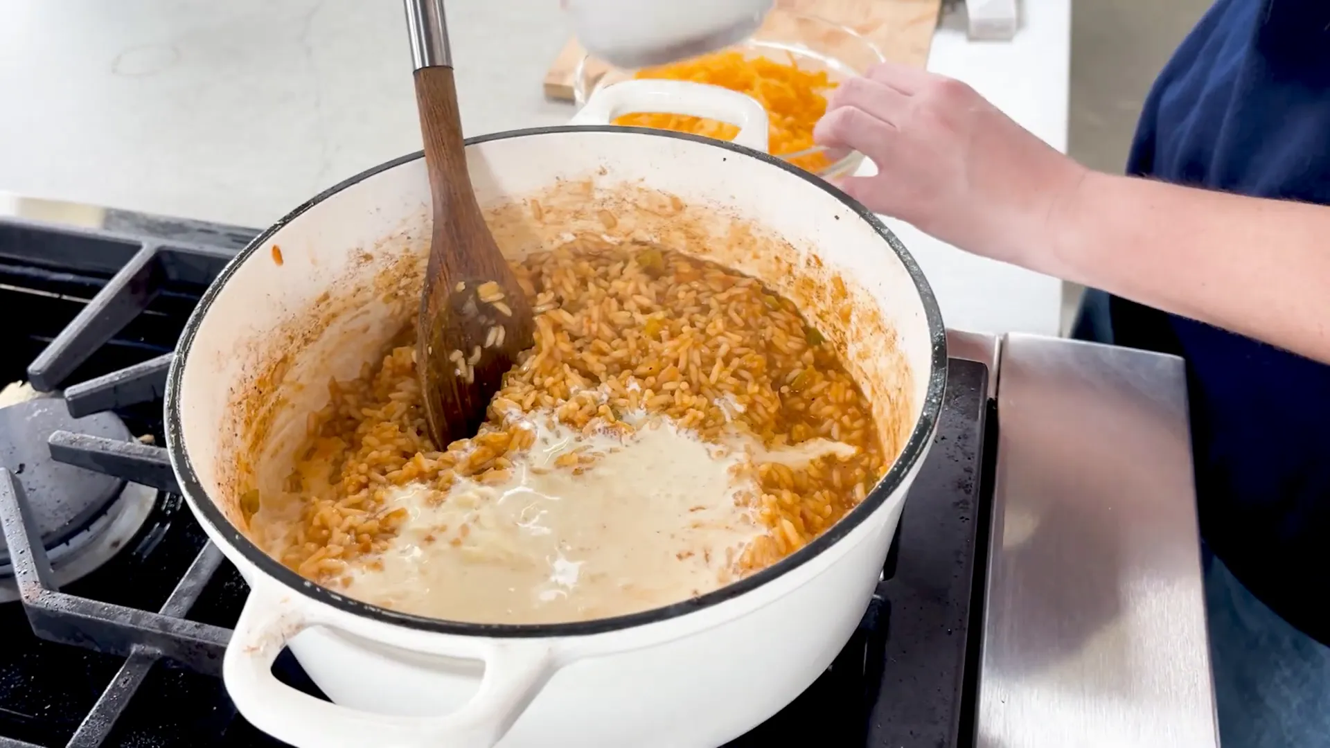 Stirring heavy cream and cheddar cheese into rice