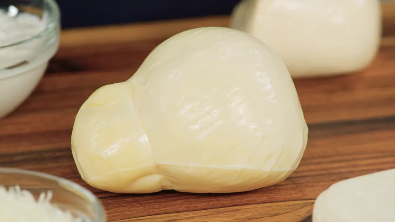 Pear-shaped scamorza or smoked mozzarella on a cutting board close up
