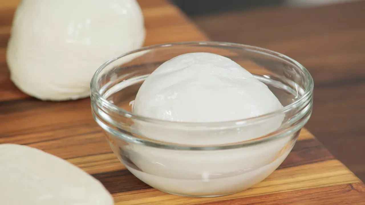 close-up of a ball of buffalo mozzarella in a glass bowl on a wooden board