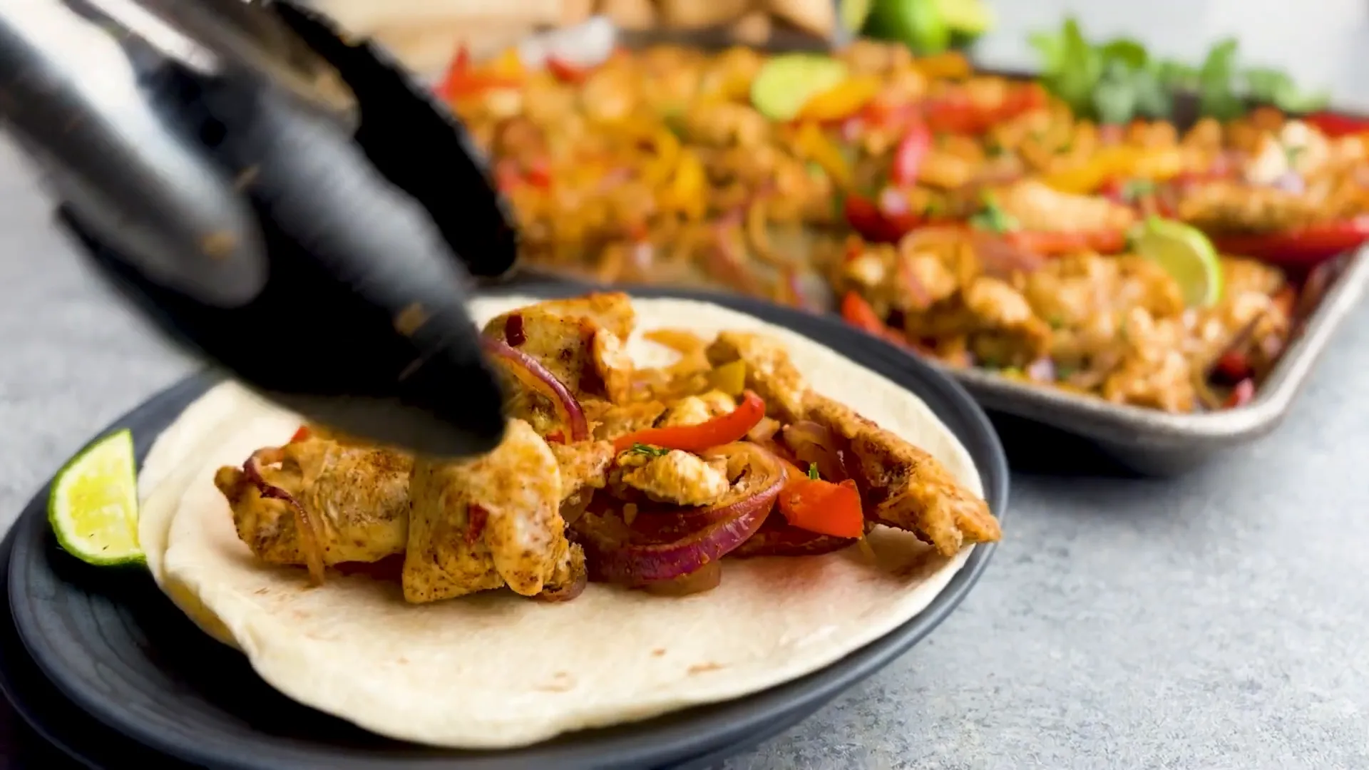 Finished chicken fajitas served with warm tortillas and sour cream