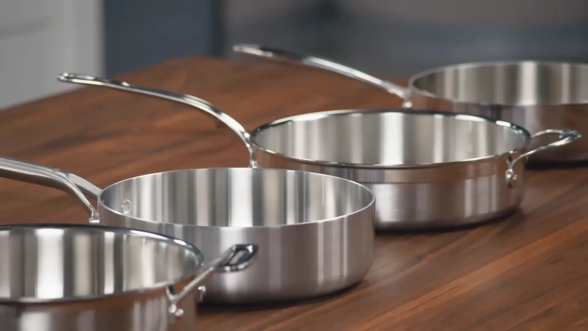 variety of sauté pans lined up on a kitchen counter