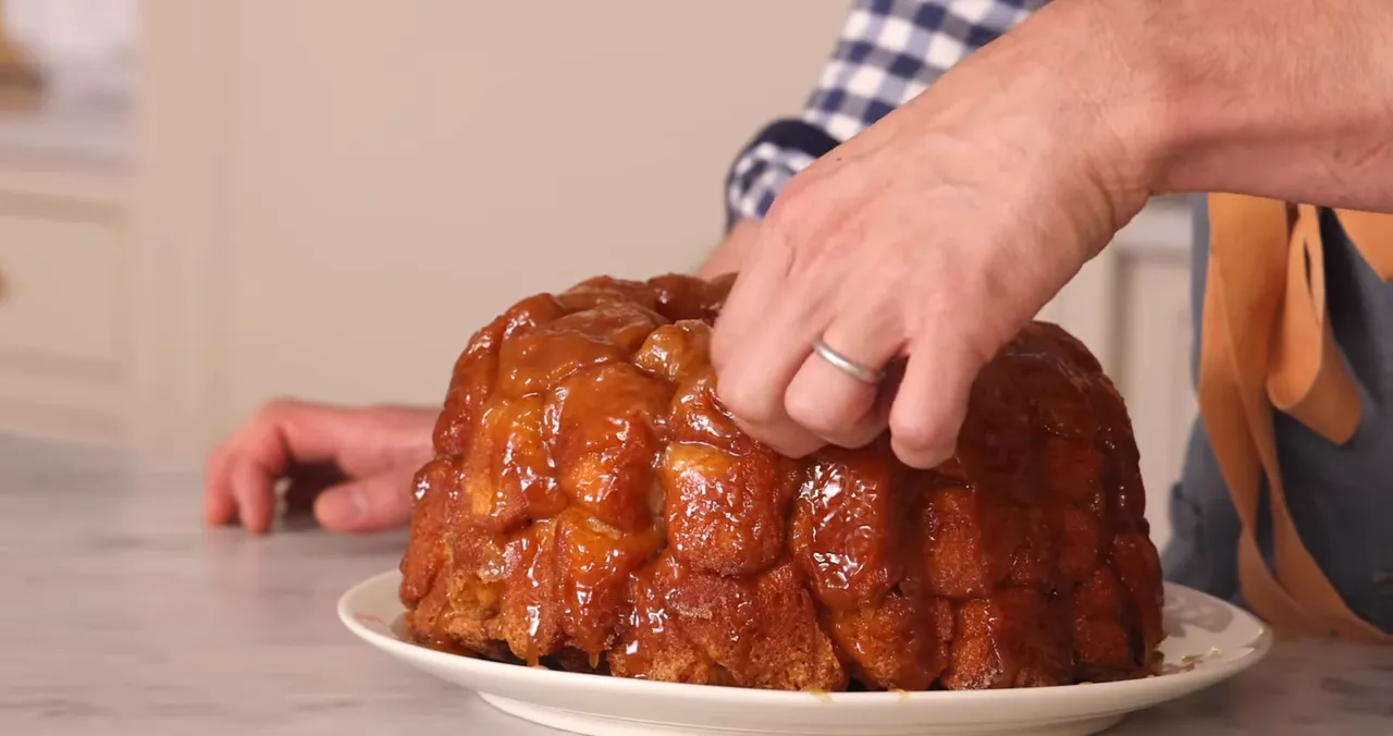 Hand pulling a piece from a caramel-covered monkey bread
