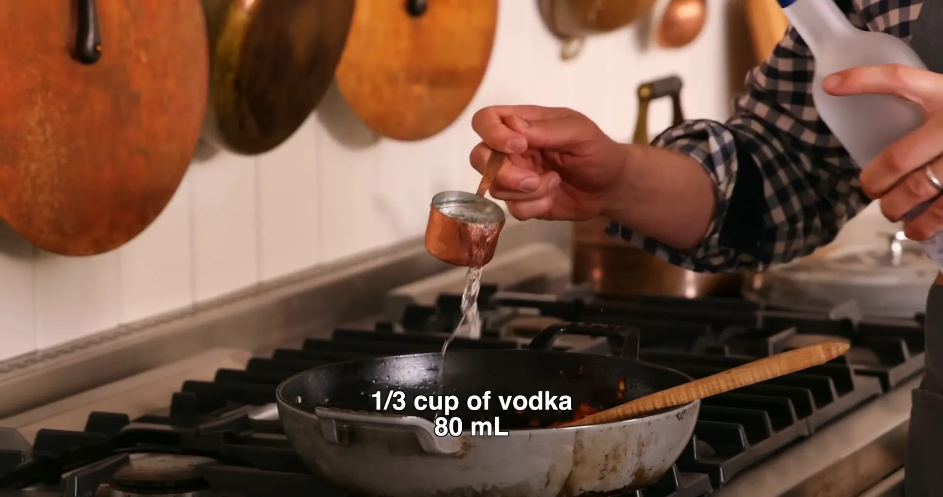 Adding vodka to tomato paste mixture in skillet