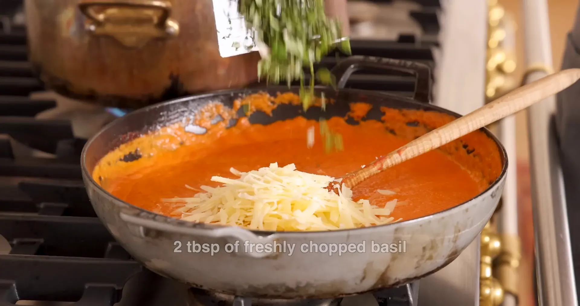 Adding Parmesan cheese and fresh basil to creamy vodka sauce
