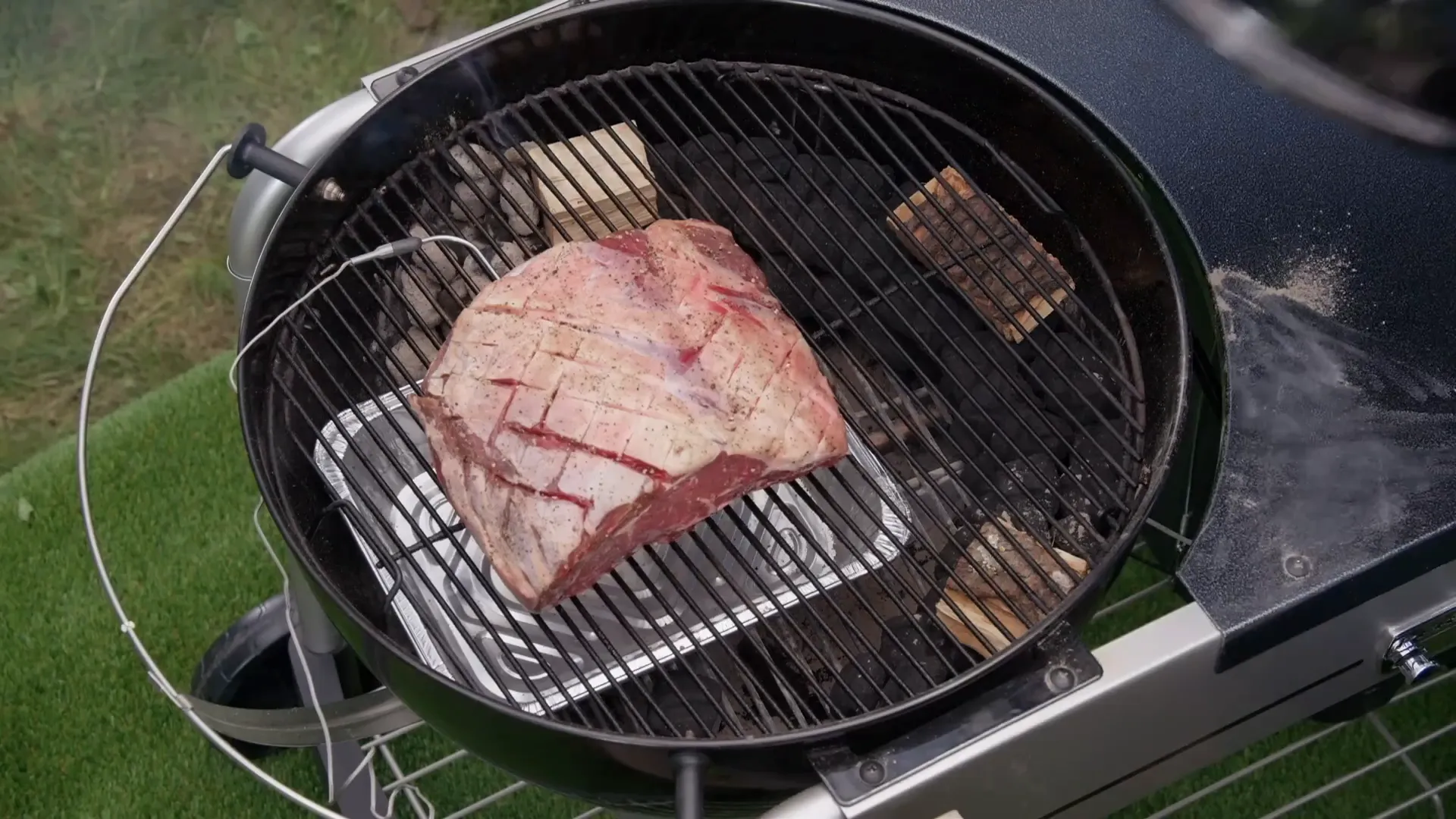 Probe thermometer inserted into roast on the grill