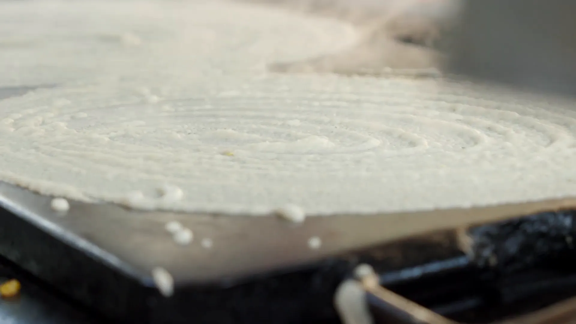Five paper-thin dosas cooking simultaneously on the griddle
