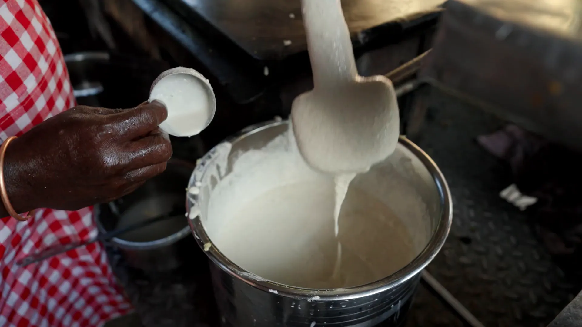 Hand-fluffed dosa batter in a large vessel after grinding