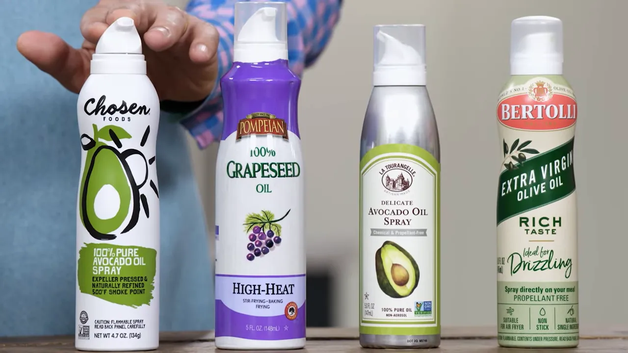 Four cooking spray cans with visible nozzle styles and a hand reaching to demonstrate aiming