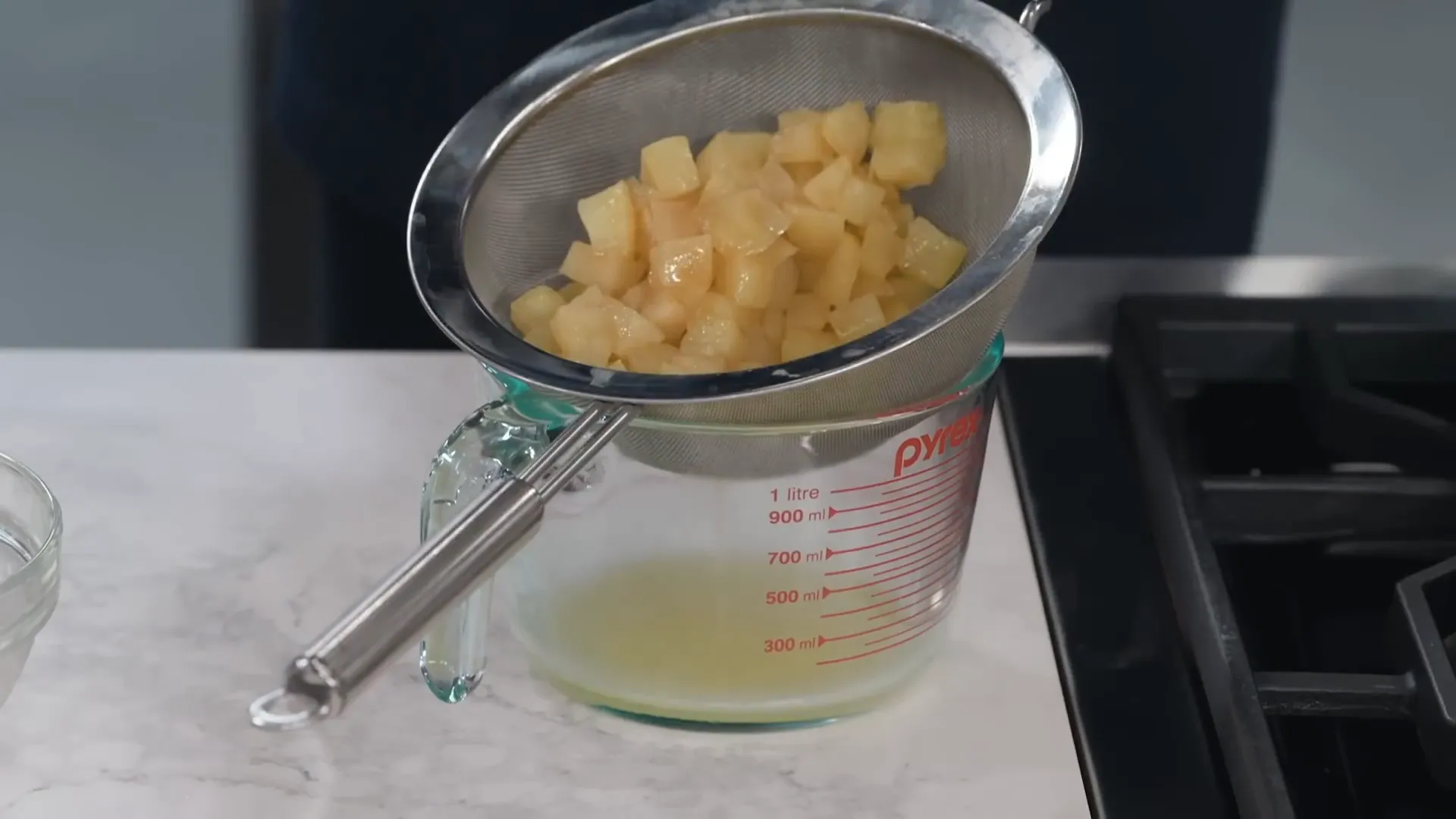 Apple cooking liquid being strained into a measuring cup