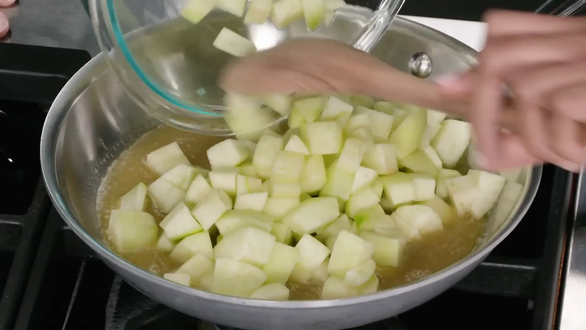 Apples cooking in butter, brown sugar, and water in a skillet