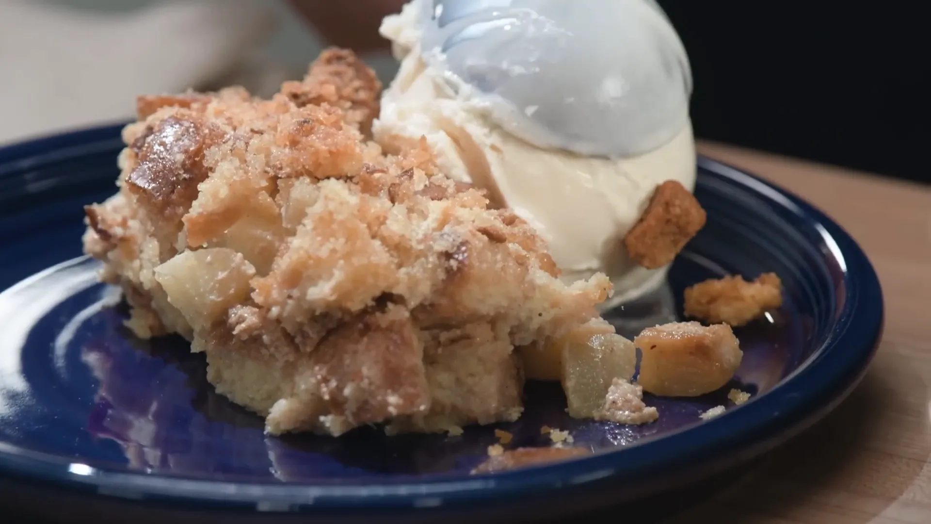Plated slice of double apple bread pudding topped with a scoop of vanilla ice cream
