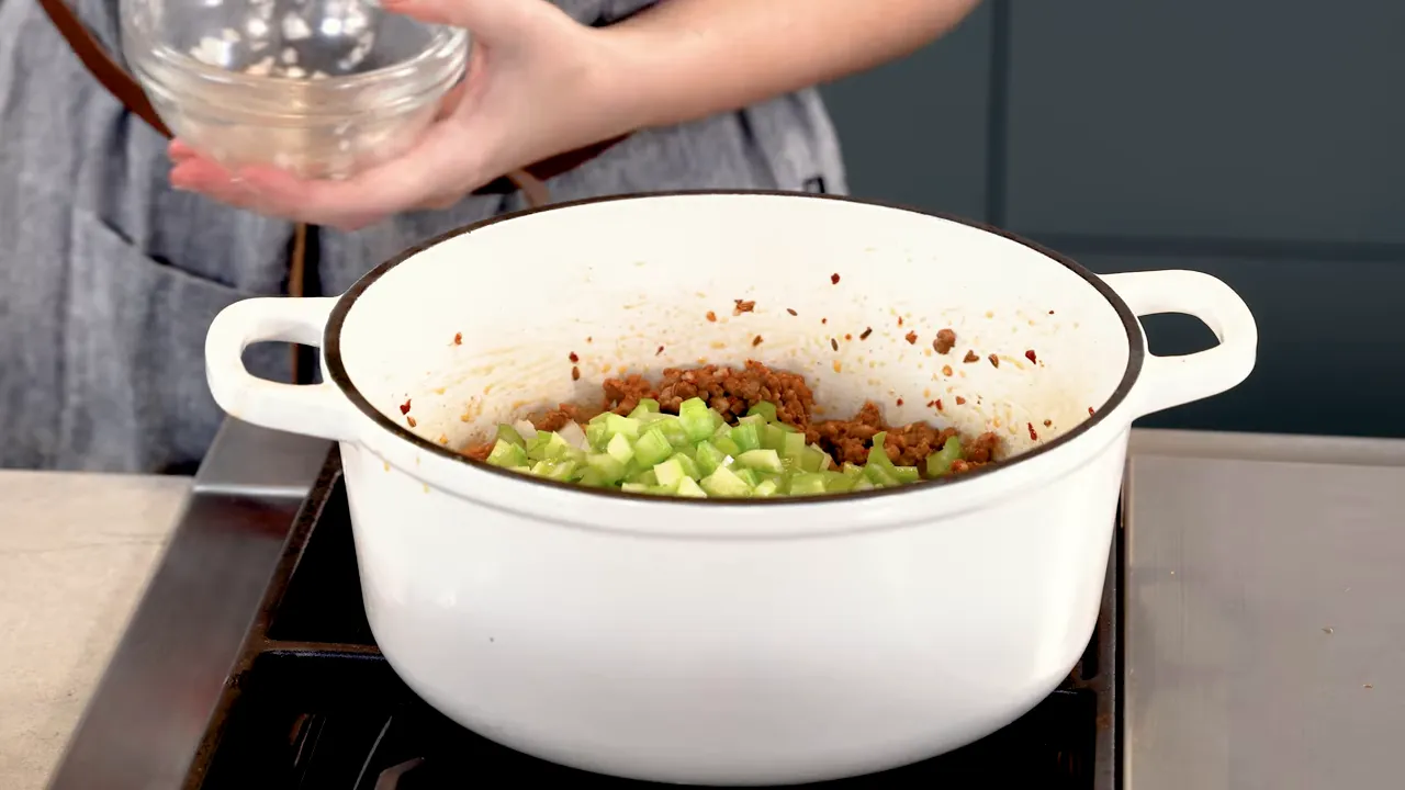 Sautéed onions, celery, and carrots with sausage in the pot