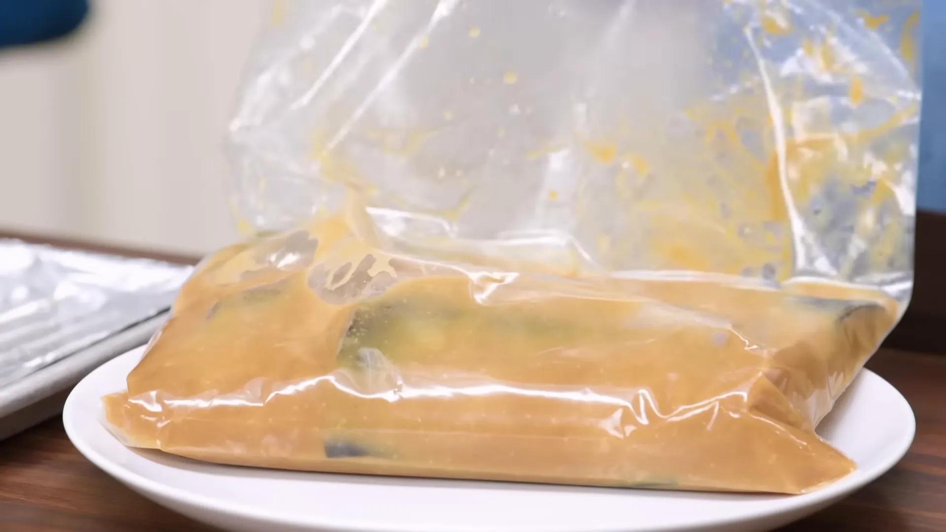 Four fillets marinating in a resealable bag on a plate