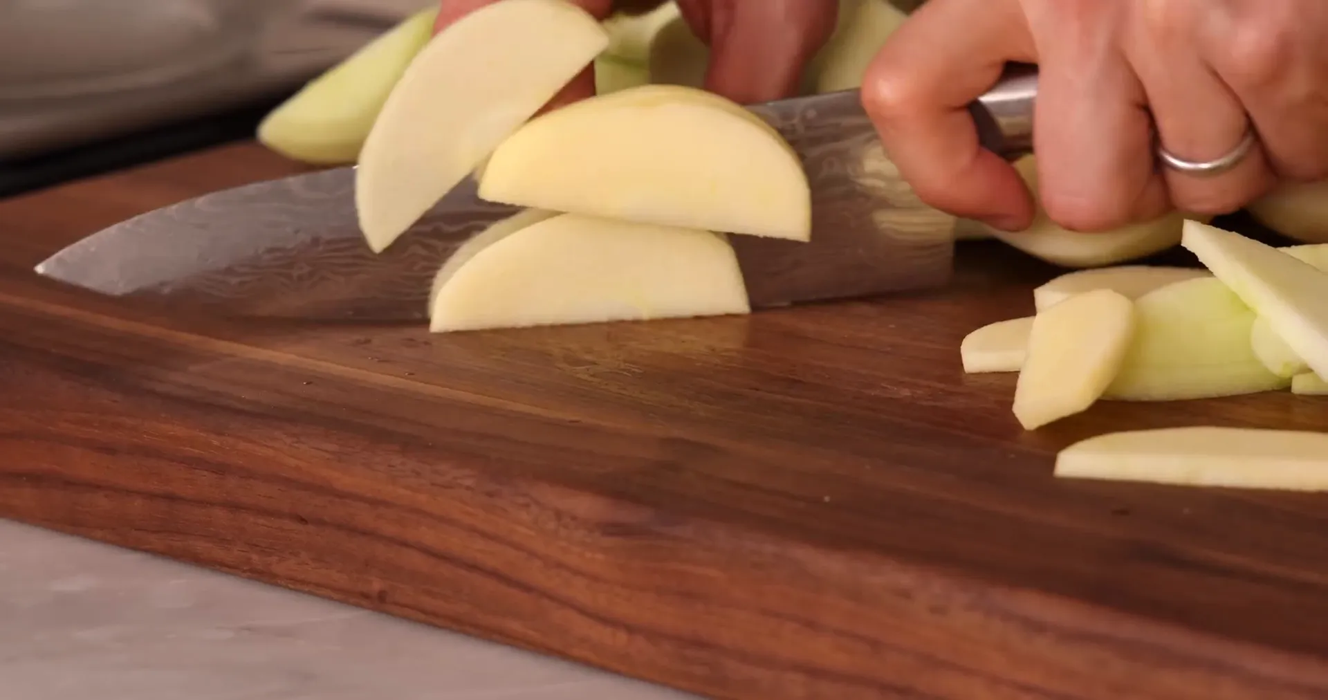 Thin apple slices being arranged on a cutting board