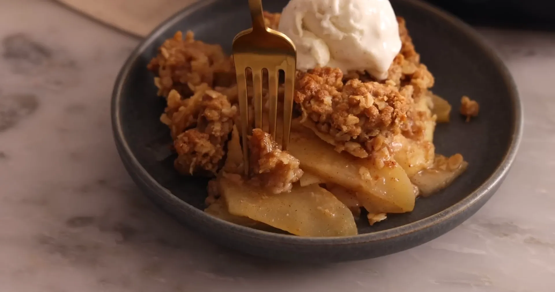 A warm square of apple crisp topped with melting vanilla ice cream