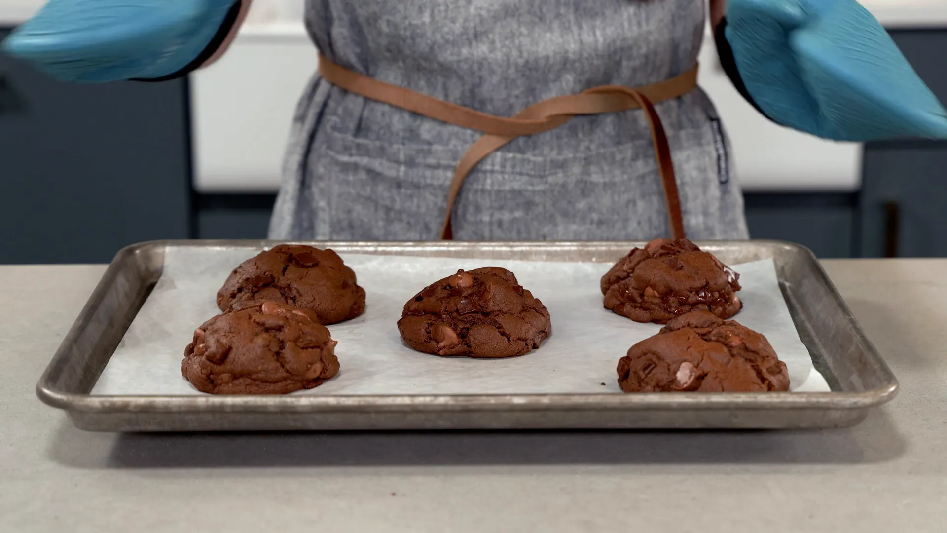 Freshly baked giant triple-chunk cookies cooling on a baking sheet
