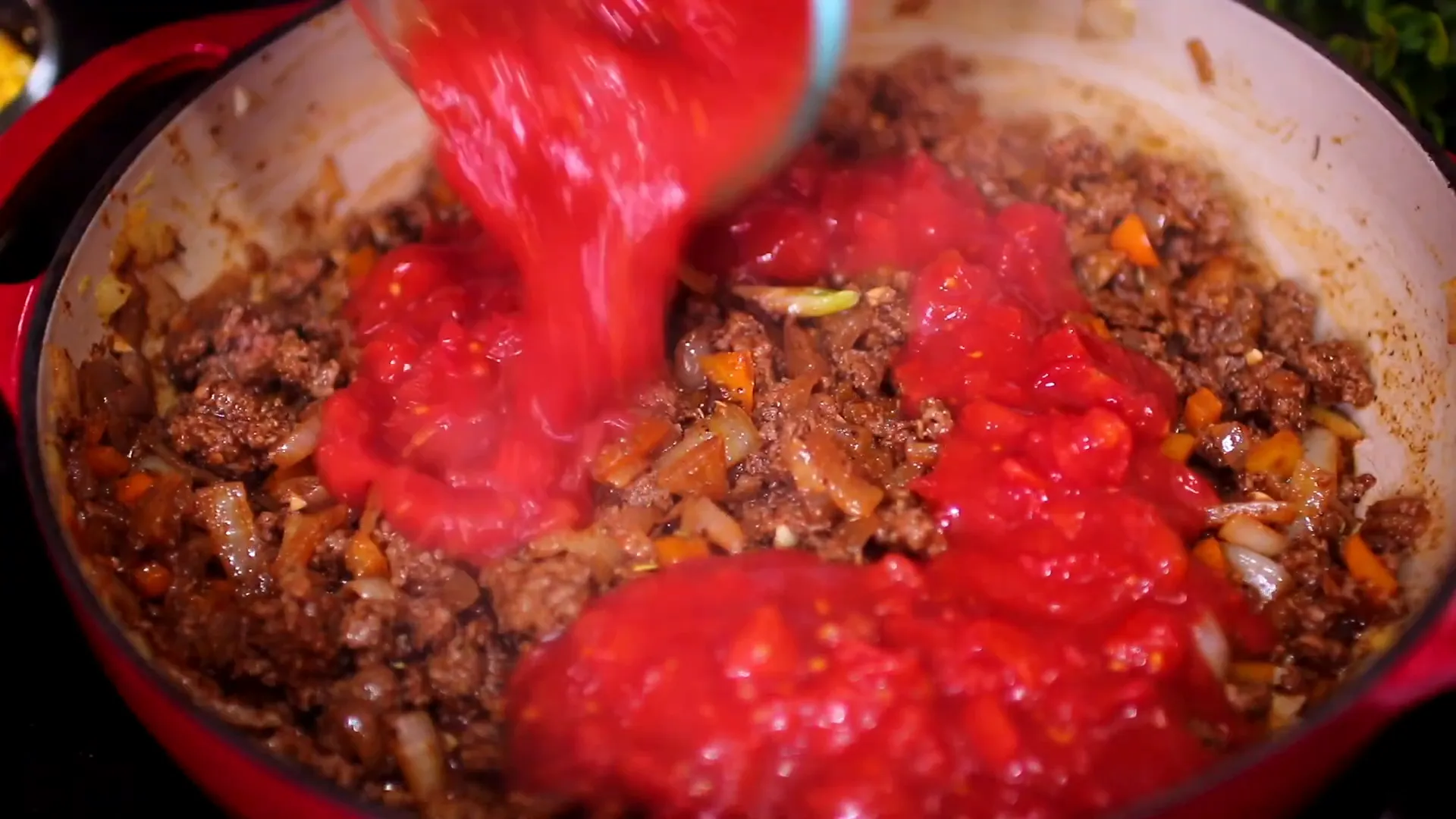 Mixing crushed tomatoes, black beans, and corn into the beef.