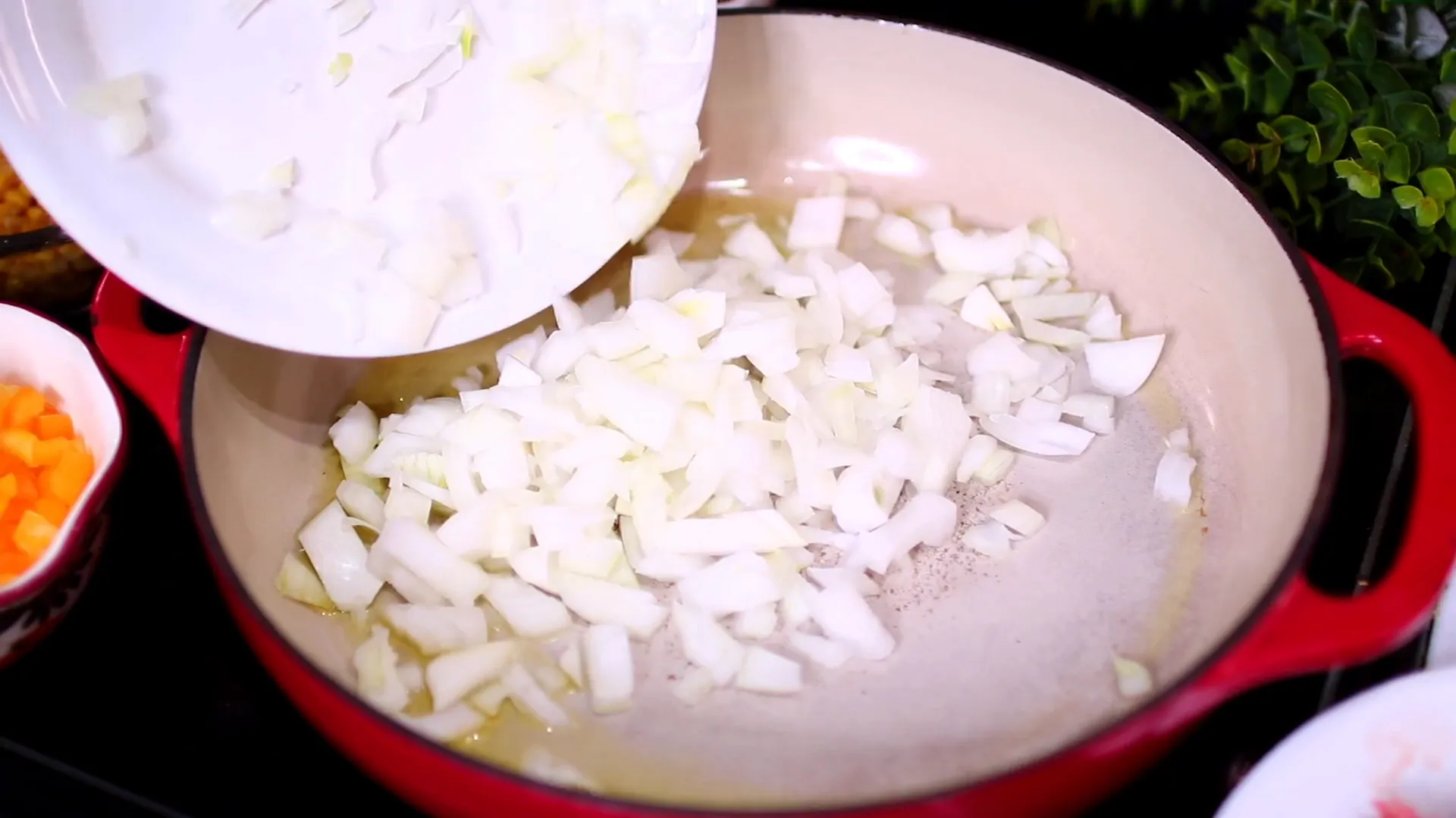 Diced onion and chopped bell pepper cooking in a skillet.