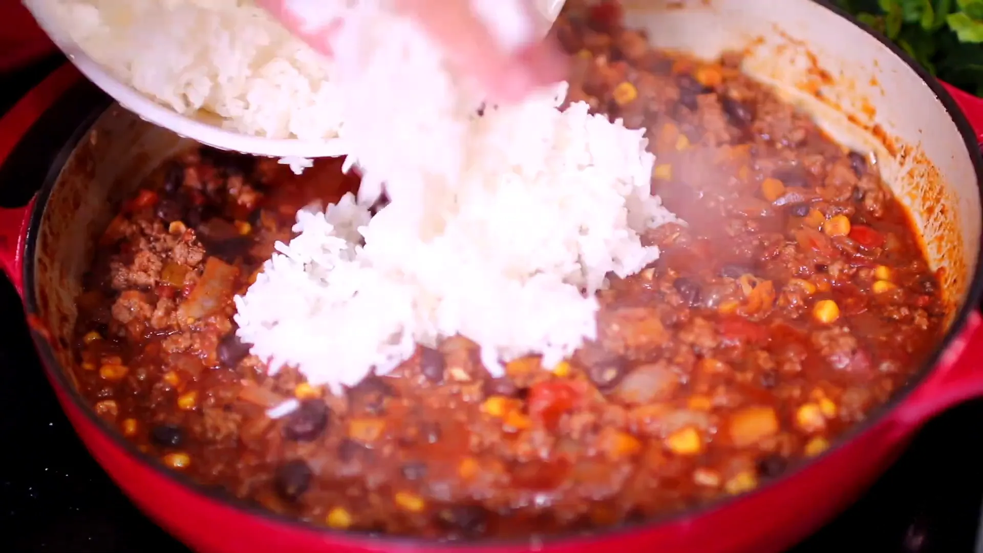 Adding cooked rice and cheddar cheese to the beef mixture.