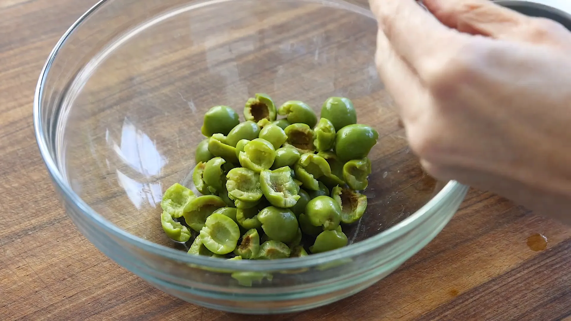 Tearing olives in half.