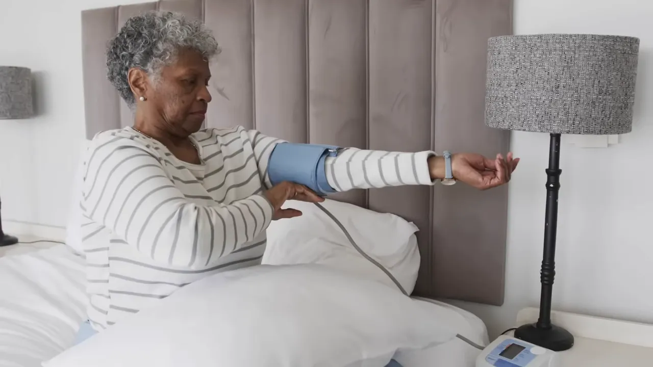 Older woman sitting in bed using an upper arm blood pressure monitor