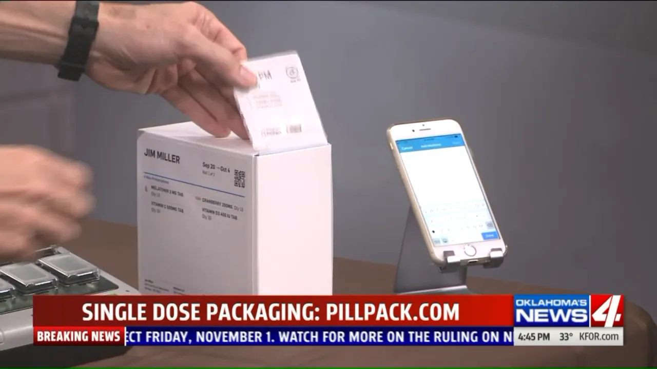 hand pulling a labeled single-dose medication packet from a white box beside a smartphone
