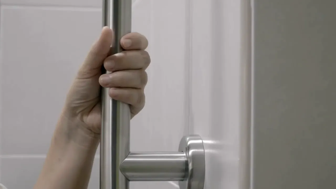 hand gripping vertical metal grab bar beside shower wall