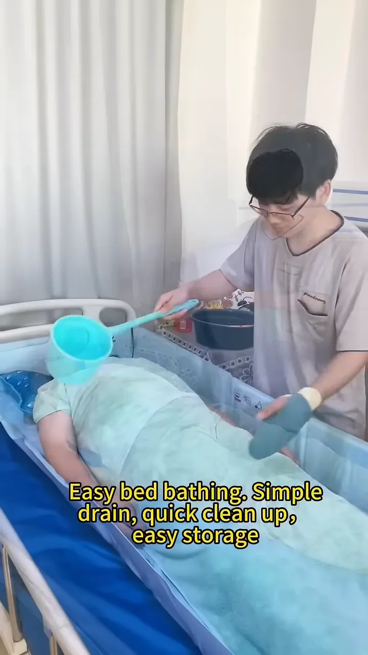 caregiver using a scoop to pour water over a person lying inside a bed bath on a hospital bed
