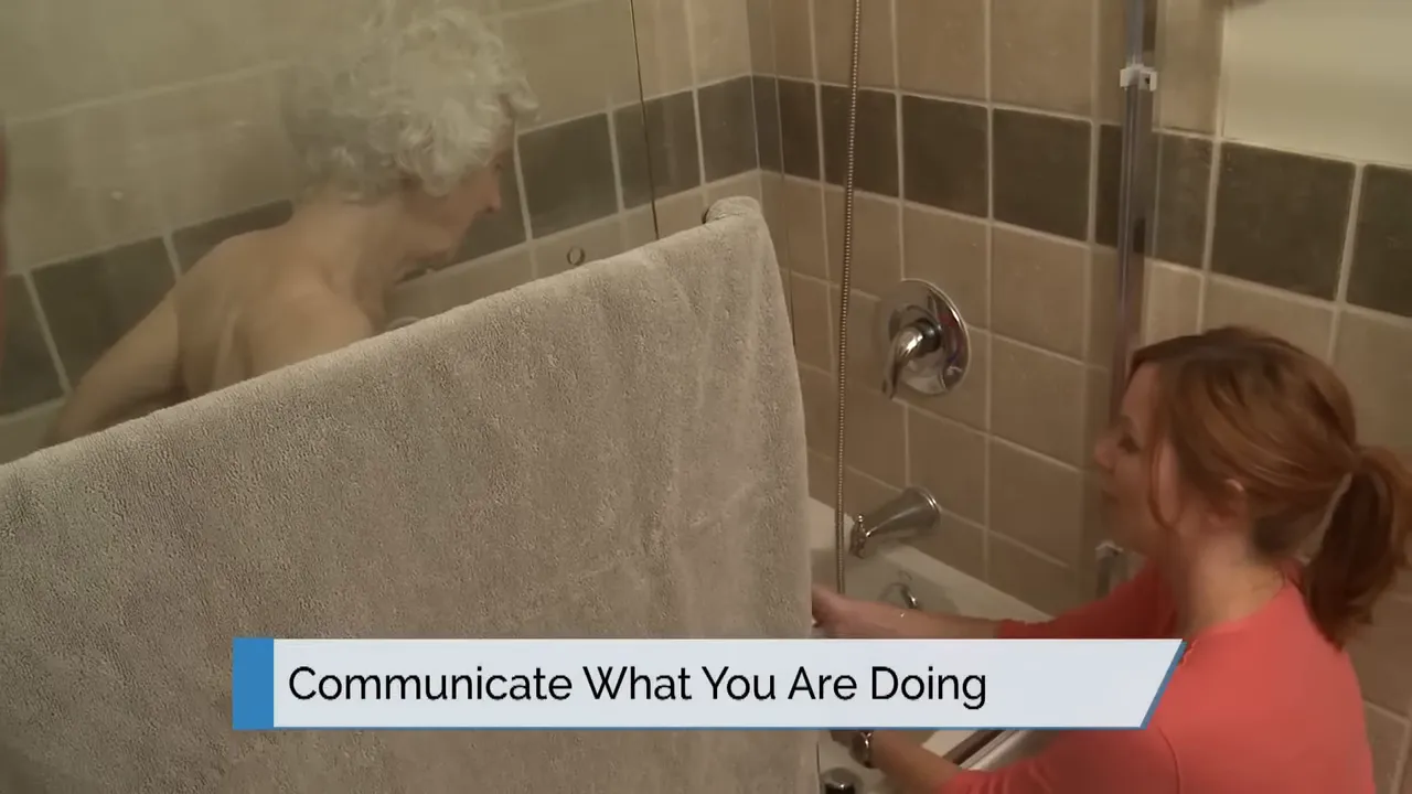 caregiver assisting in bathtub with on screen text communicate what you are doing