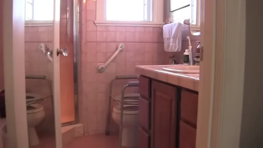 Bathroom with shower toilet sink grab bar and chair visible