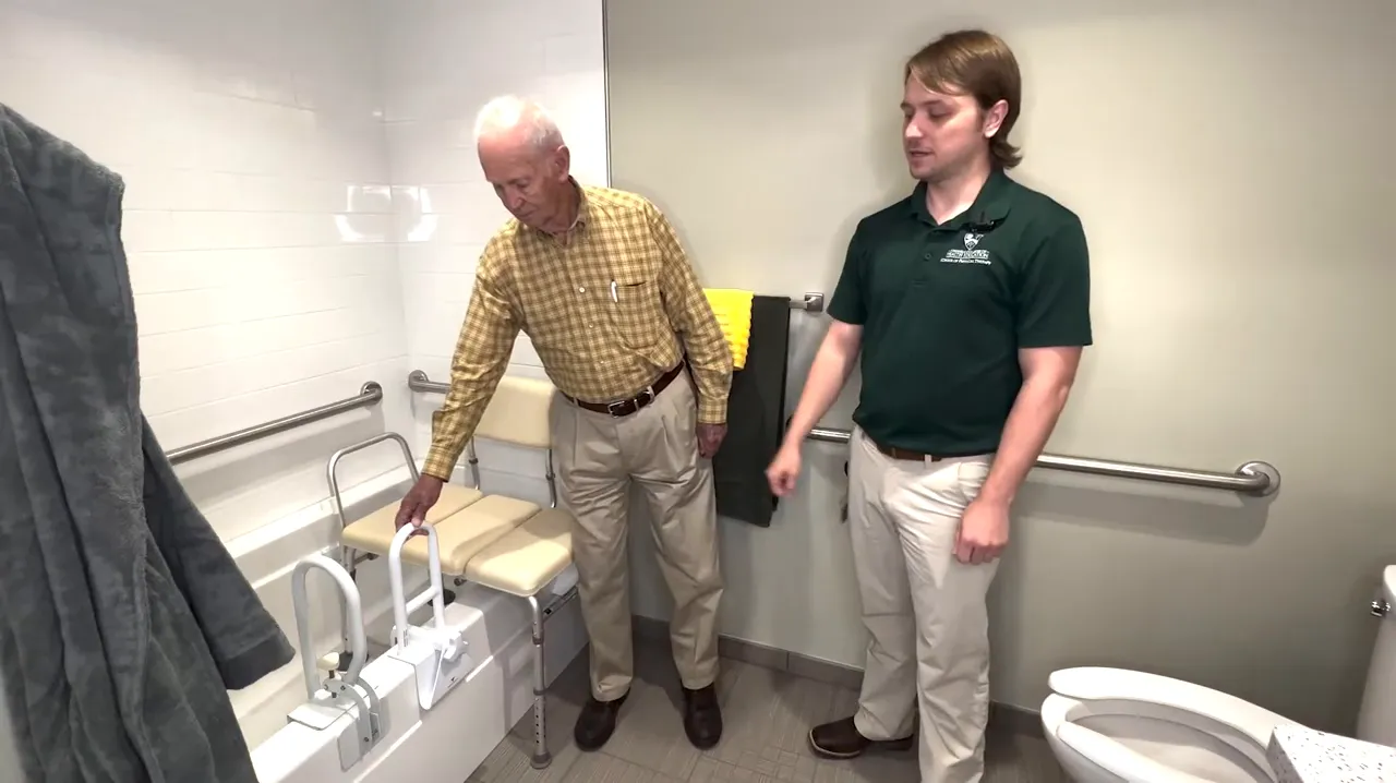Bathtub with mounted grab bars and a transfer bench beside the tub