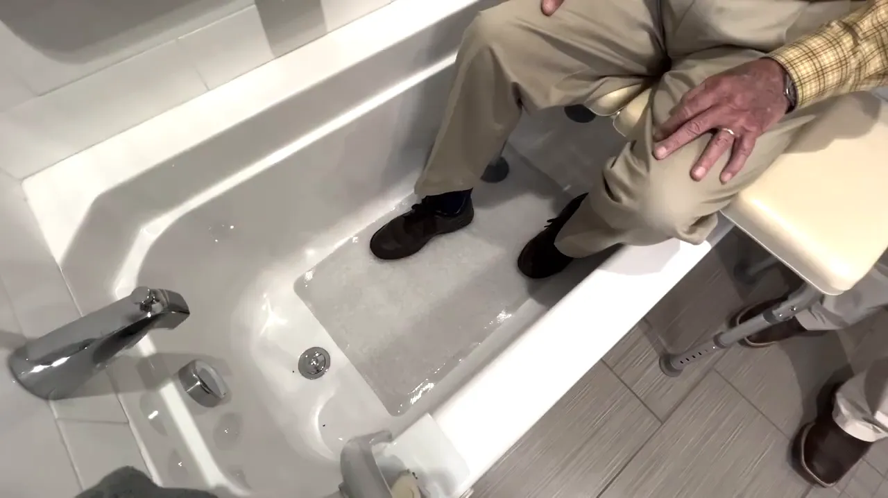Bathtub floor with a non-slip bath mat visible near the drain