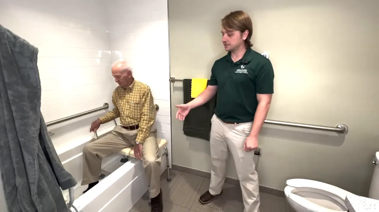 Older adult seated on a tub transfer bench with both legs moving into the bathtub