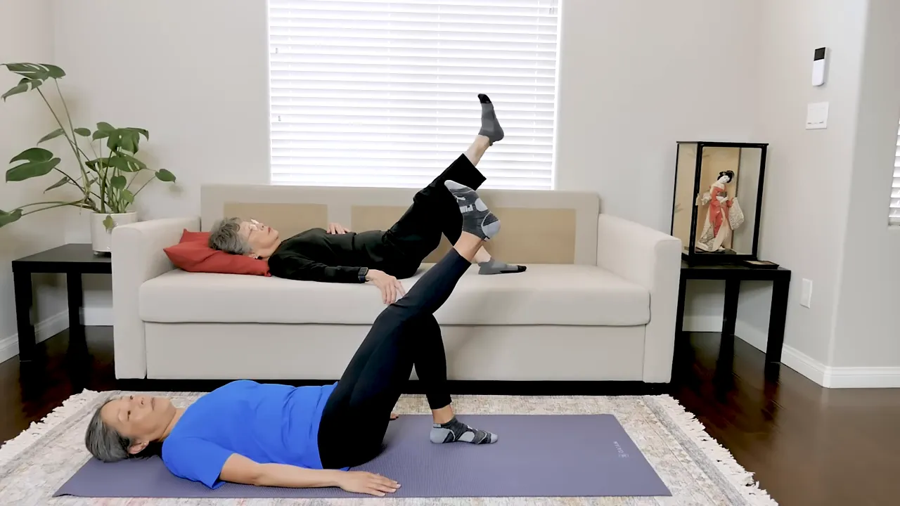 Two exercisers lying down performing a straight leg raise with one leg lifted upward