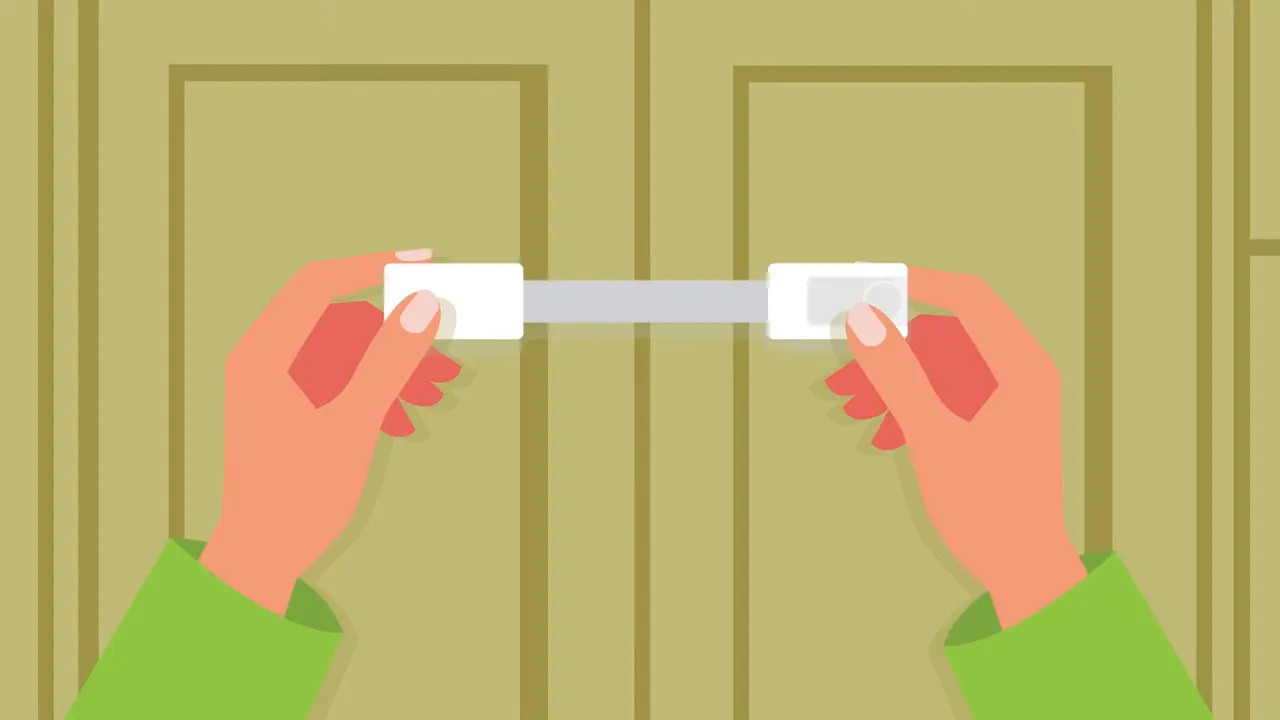 Hands securing a white safety lock across cabinet doors