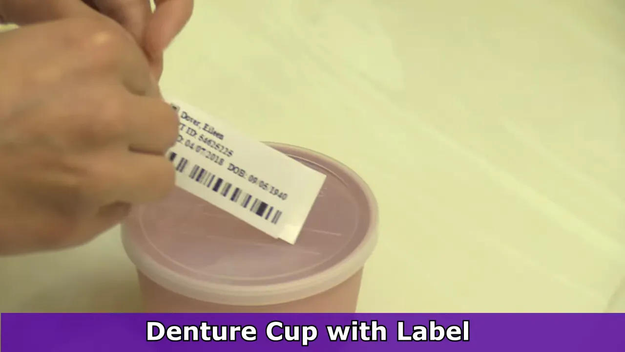 Pink denture cup with a patient label on the lid