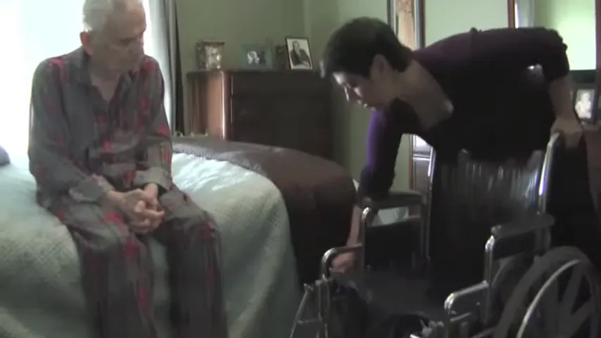 Wheelchair positioned beside a bed with footrests and arm area visible