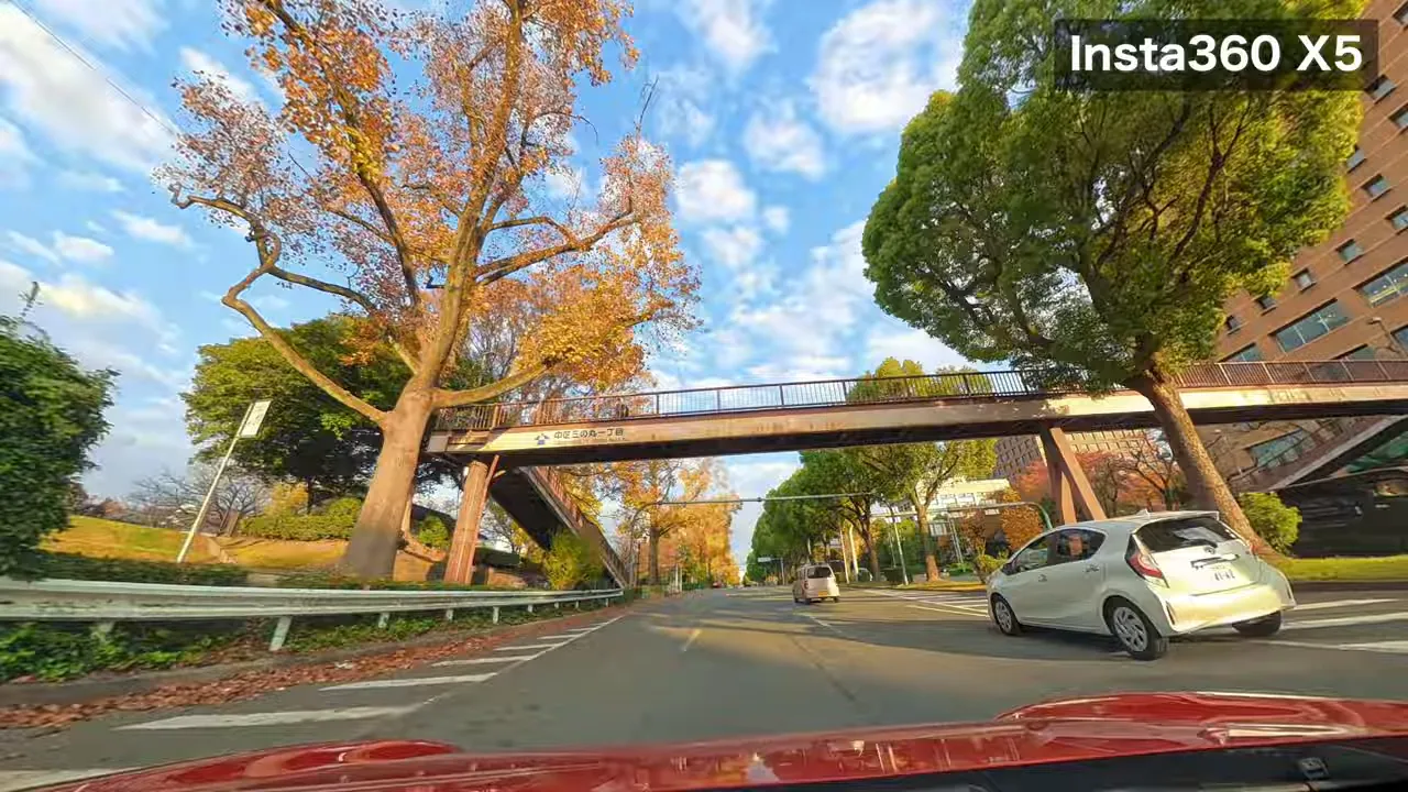 Insta360 X5で撮影した名古屋城周辺の昼景、歩道橋越しに紅葉した木々と右手の建物が鮮明に写る