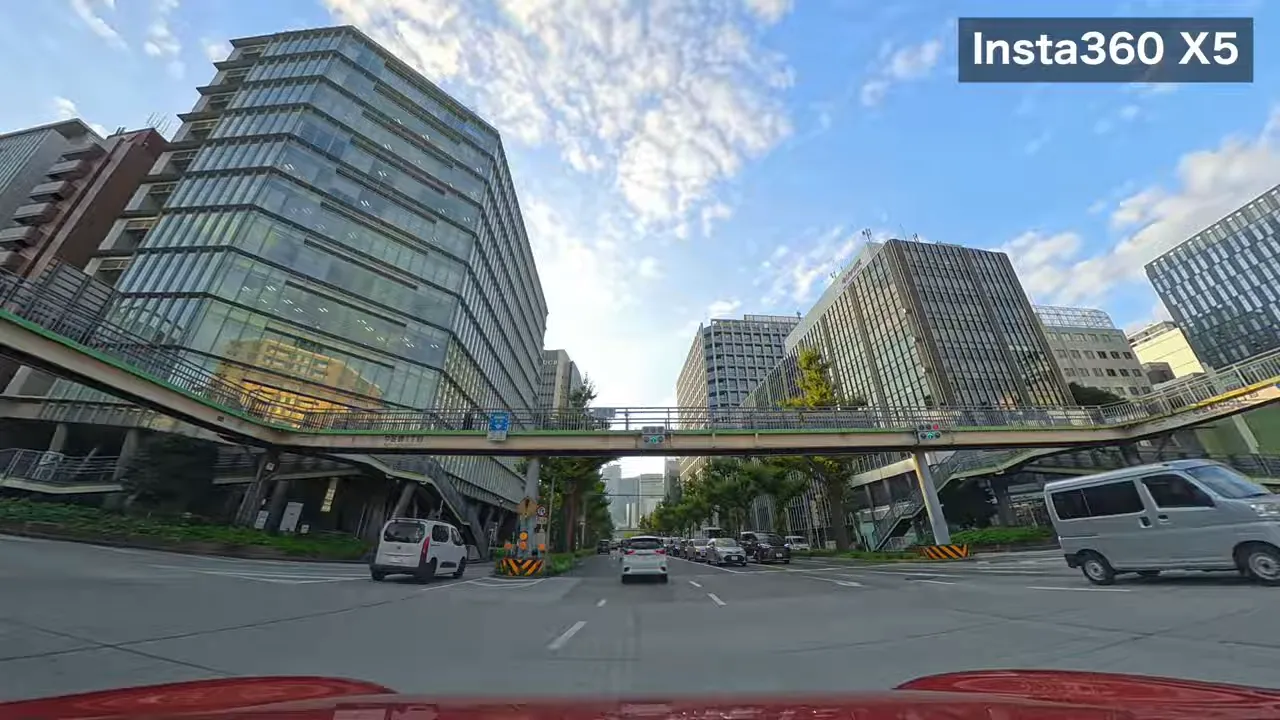 Insta360 X5で撮影した名古屋駅周辺の昼間の車載ショット、中央の歩道橋と左右に並ぶガラス張り高層ビルがはっきり写る