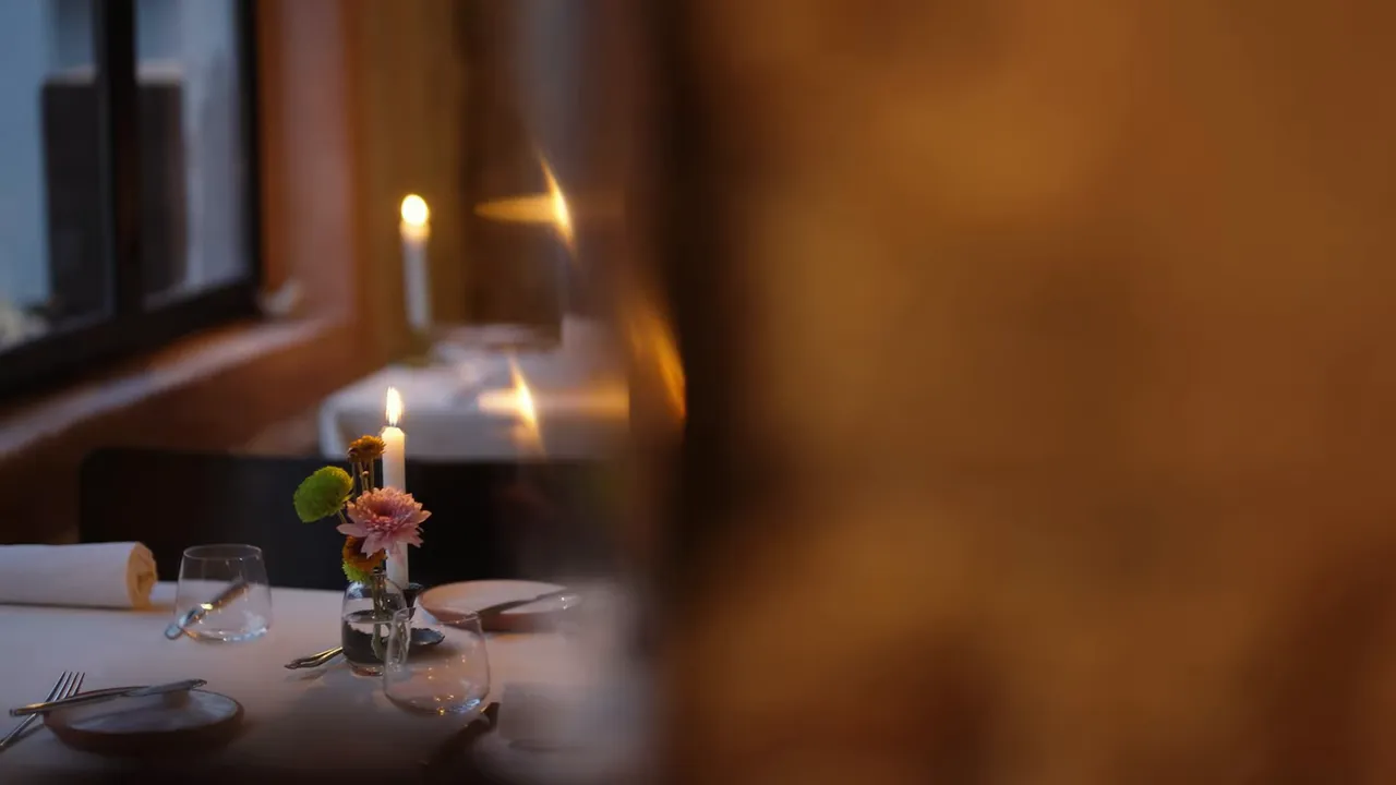 Candlelit restaurant table with small floral arrangement and glassware