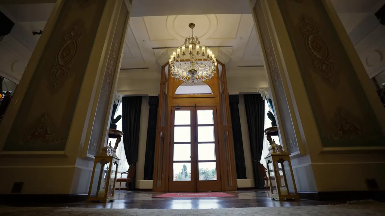 Grand hotel entrance with double doors, crystal chandelier and ornate foyer