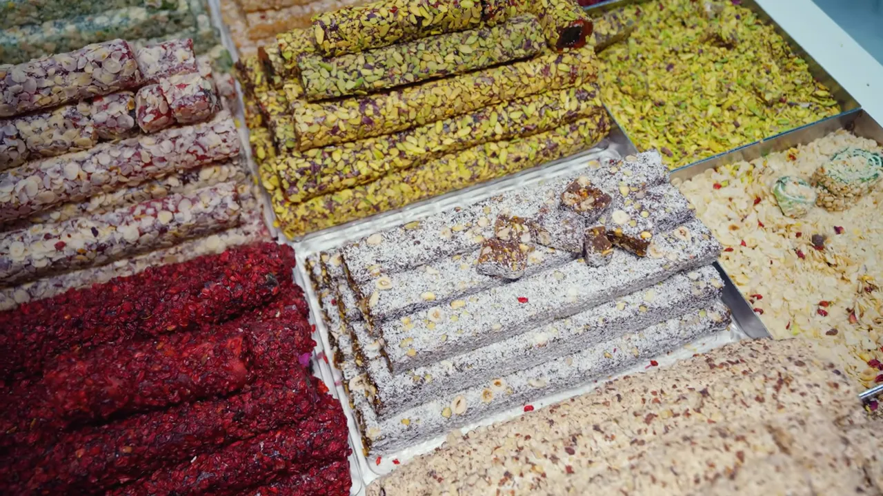 Close-up of multiple lokum rolls coated with pistachios, shredded coconut and rose bits