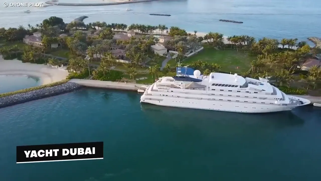 aerial view of the superyacht Dubai moored by a beachfront with palm trees and calm water