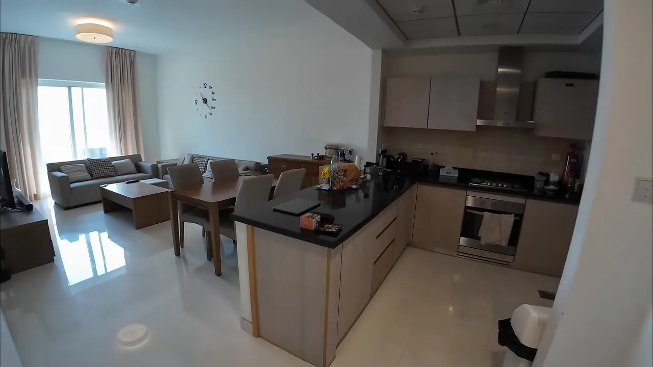 Aydınlık oturma odası ve a&ccedil;ık mutfak, yemek masası ve kanepeler.