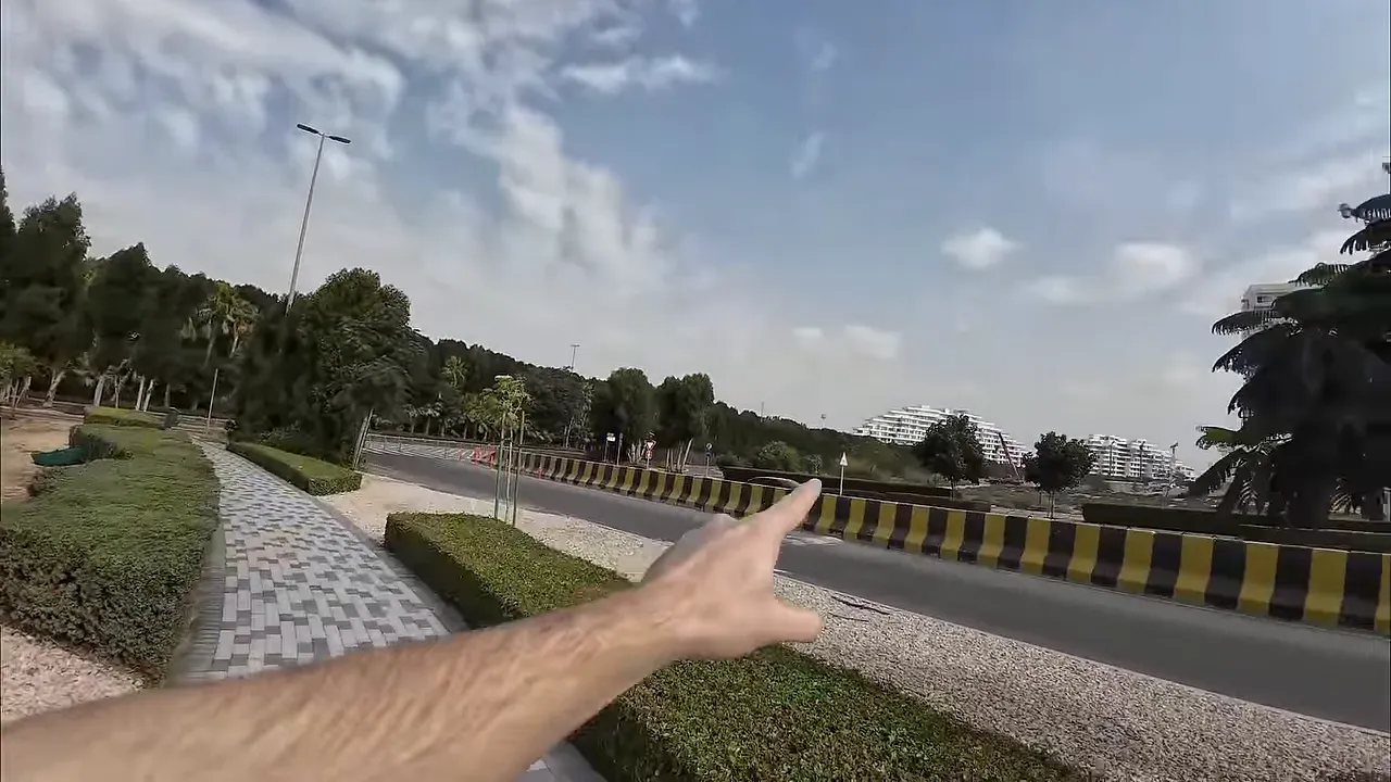 Bir elin caddeye işaret ettiği Dubai sokak manzarası, y&uuml;r&uuml;y&uuml;ş yolu ve uzakta apartmanlar