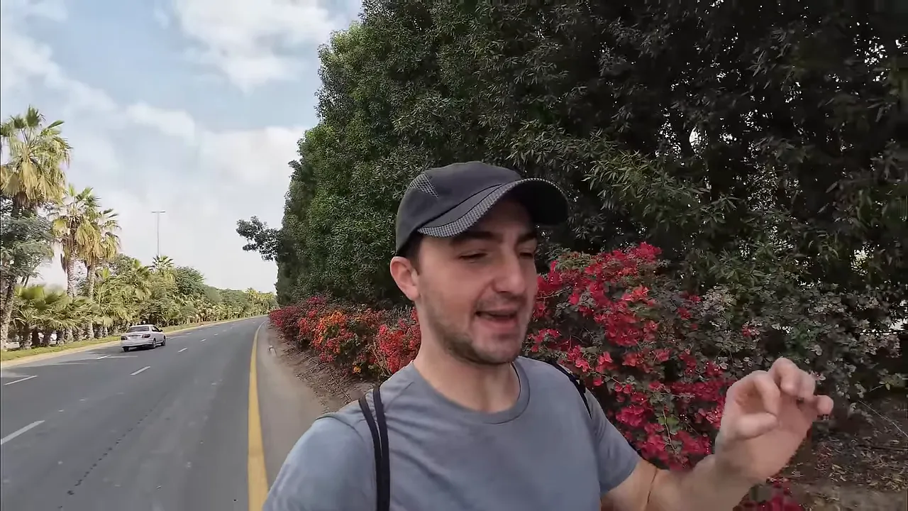 Geniş &ccedil;ok şeritli yol boyunca y&uuml;r&uuml;yen kişi, yolda bir otomobil ve palmiye ağa&ccedil;ları