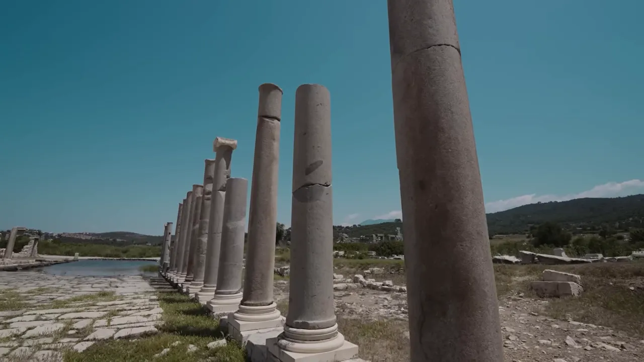 Line of standing Roman columns along a paved walkway at Patara ruins with landscape beyond
